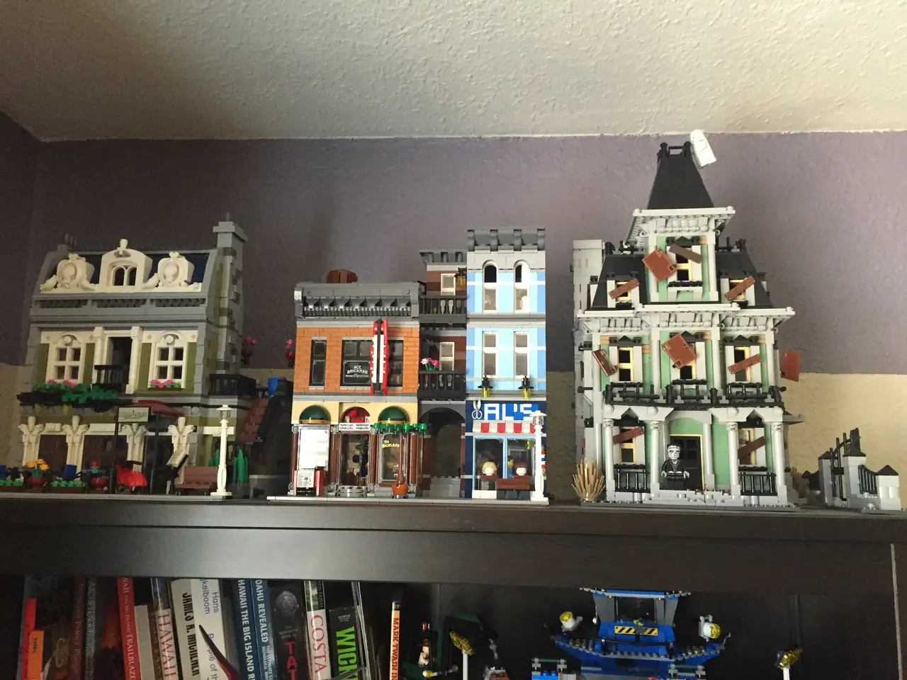 Several assembled LEGO buildings displayed together on a shelf